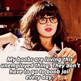 Zooey Deschanel as Jessica Day in the sitcom "New Girl" sitting on a couch with messy hair, glasses and red lipstick gesturing at her chest with her laptop in front of her